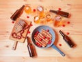 Frying pan with roasted sausages, beer bottles, mugs and glasses, bread and little chorizo sausages. Top view Royalty Free Stock Photo