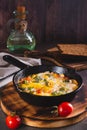 Frying pan with scrambled eggs with broccoli and tomatoes on a wooden board vertical view Royalty Free Stock Photo