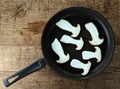 Frying pan with sliced king trumpet mushrooms on a background of wood Royalty Free Stock Photo
