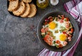 Frying pan with tasty cooked egg, sausages and vegetables on grey table.