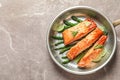 Frying pan with tasty cooked salmon on table