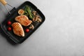 Frying pan with tasty grilled chicken fillets and vegetables on light grey table, top view. Space for text Royalty Free Stock Photo