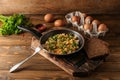 Frying pan with tasty omelet and bread on wooden table Royalty Free Stock Photo