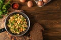 Frying pan with tasty omelet and bread on wooden table Royalty Free Stock Photo
