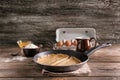 Frying pan with tasty thin pancakes and ingredients on wooden table