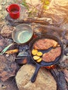 Frying pans on a campfire at a campsite. Steaks are grilled over a fire in nature Royalty Free Stock Photo
