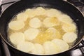 Frying rounded potatoes on a black pan with boiling oil Royalty Free Stock Photo