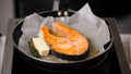 Frying salmon steak on parchment paper with butter