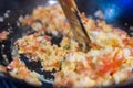 Frying and stirring eggs and traditional pico de gallo in a frying pan