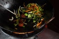 Frying vegetables in a wok pan onions, broccoli, tomatoes cherry, carrot, asparagus