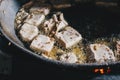 Frying White tofu in aluminum pan. Healthy food prepared in unhealthy burnt oil