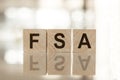 FSA - an abbreviation of wooden blocks with letters on a white background. Reflection of the caption on the mirrored surface of Royalty Free Stock Photo
