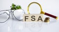 FSA concept on wooden cubes and flower ,glasses ,coins and magnifier on the white background Royalty Free Stock Photo