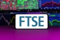 FTSE 100 stock market index in front of stock market charts background