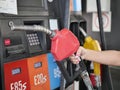 fuel dispenser in gas station. woman holding a red fuel dispenser. Petrol stations are classified by color. Royalty Free Stock Photo