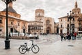 Fuente del Turia fountain, bicycle and tourists at Valencia Cathedral square with church and bell tower in background