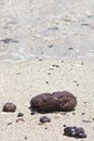 Volcanic Pebbles on a sandy beach with the gentle calm waves lapping behind Royalty Free Stock Photo