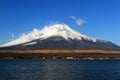 Fuji mountain with snow and fog covered top, lake or sea and clear blue sky background with copy space. Royalty Free Stock Photo