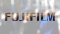 Fujifilm logo on a glass against blurred crowd on the steet. Editorial 3D rendering Royalty Free Stock Photo