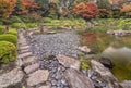 Autumn landscape with pebbles wet by rain and momiji trees around the pond of Ohori garden.