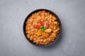 Ful Medames or Fava Beans in black bowl at grey backdrop. Foul Mudammas is a Egyptiancuisine breakfast dish