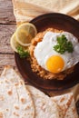 Ful medames with a fried egg and bread close-up. vertical top vi