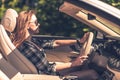 A fulfilled young woman driving a convertible during sunset.