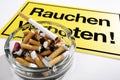 Full ashtray in front of no smoking signboard Royalty Free Stock Photo