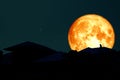 full blood moon back over silhouette roof