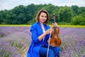 Full body adult woman violinist playing violin and sitting on lavender field Royalty Free Stock Photo