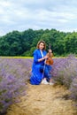 Full body adult woman violinist playing violin and sitting on lavender field Royalty Free Stock Photo