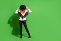 Full body back photo of orange hairdo lady stand touch hat wear shirt trousers shoes isolated on green background
