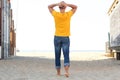 Full body from behind of man walking barefoot on beach with hands behind head Royalty Free Stock Photo