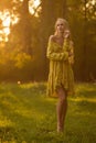 Blond woman resting in forest at sunset