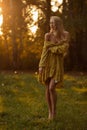 Blond woman resting in forest at sunset