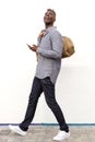 Full body cheerful young black man walking with handbag and smart phone Royalty Free Stock Photo
