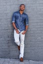 Full body cool young black guy leaning against gray wall Royalty Free Stock Photo