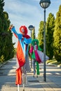 Creative clowns on stilts walking on pathway in sunny park