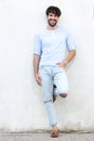 Full body handsome young man leaning against white wall and smiling Royalty Free Stock Photo