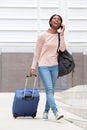 Full body happy young african american woman walking with suitcase bag and mobile phone Royalty Free Stock Photo