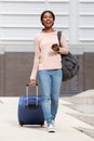 Full body happy young african american woman walking with suitcase bag and smart phone Royalty Free Stock Photo