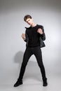 Full body image of model appearance of young fashionable guy in leather jacket and all black clothes posing on white