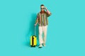 Full body length photo of cool successful businessman irish traveler touch sunglass with suitcase  on aquamarine Royalty Free Stock Photo