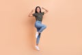 Full body length photo of funky girl vietnamese jump v-sign face peace symbols wear khaki t-shirt jeans isolated on
