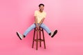 Full body length photo of young overjoyed man sitting stool carefree have fun positive good mood isolated on pink color