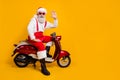 Full body photo of aged white haired santa ready for x-mas newyear party sitting vintage bike waving arm wear sun specs Royalty Free Stock Photo