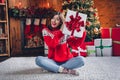 Full body photo of attractive overjoyed girl wear red ugly sweater celebrate hold shaking white package present sitting Royalty Free Stock Photo