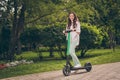 Full body photo of attractive young active girl ride electric scooter happy smile fun in park green trees nature