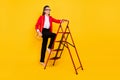 Full body photo of bossy elder woman go upstairs wear cardigan pants stilettos purse bag isolated on yellow background Royalty Free Stock Photo