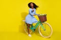 Full body photo of brunette afro american wear red headband blue dotted dress bike send air kiss on yellow